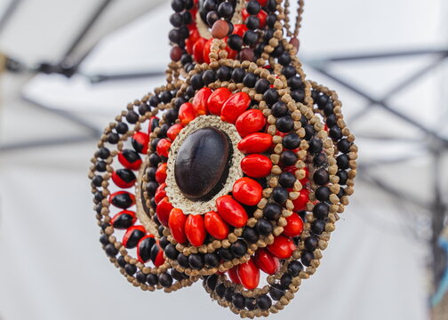 A traditional medallion necklace handcrafted from red and dark seeds, created by indigenous Kichwa women in the Pastaza province of the Ecuadorian Amazon