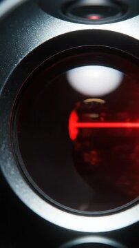 Close-up of a red laser beam visible through a magnifying lens with bokeh background.