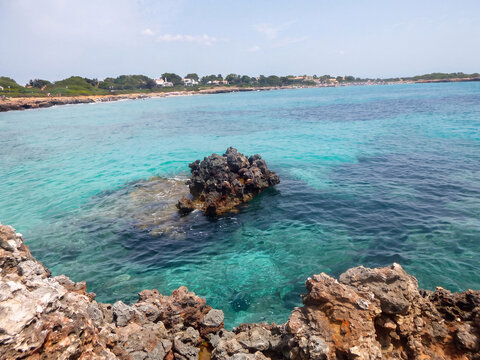 Eaux turquoise cristallines d'un lagon m&eacute;diterran&eacute;en avec des rochers affleurant &agrave; la surface, vue a&eacute;rienne d'une plage paradisiaque id&eacute;ale pour la baignade et la d&eacute;tente en &eacute;t&eacute;