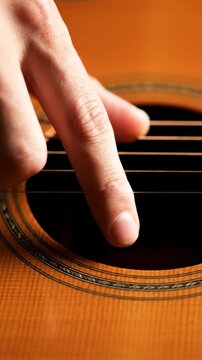 Close-up of fingers playing acoustic guitar strings. Musical hobby.