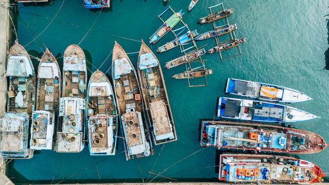 Aerial view of traditional fishing boats moored in the harbor with clear turquoise water in Palabuhanratu, Indonesia.