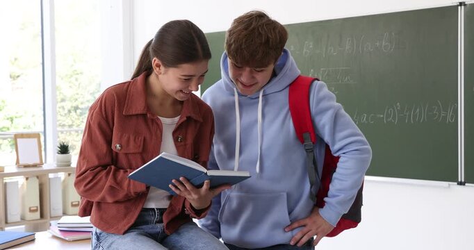 Teenage girl with book and her classmate in classroom