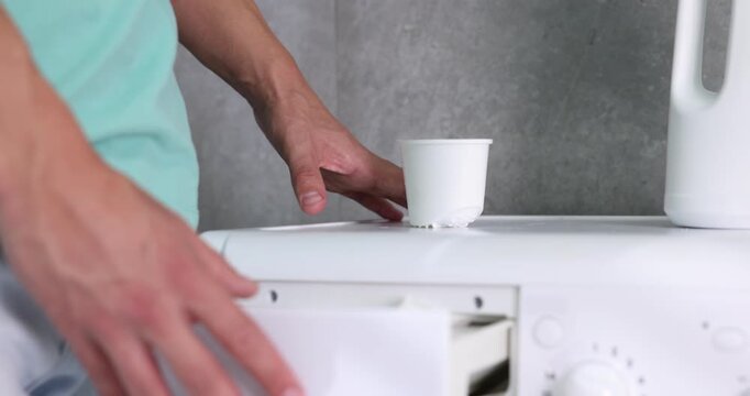 Man pouring powder into washing machine detergent compartment and closing it, closeup. Laundry day