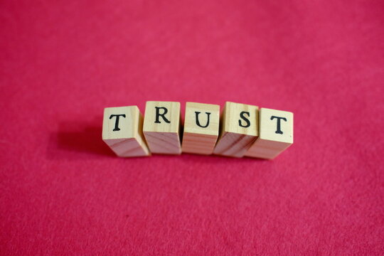 Wooden letters forming TRUST word on deep pink background, trust and relationship concept. Wooden letters forming TRUST, credibility and transparency concept