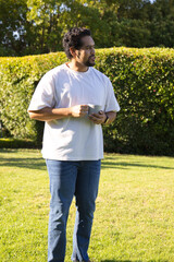 Mid adult African man standing on sunlit lawn wearing white tee holding ceramic mug looking right © wavebreak3