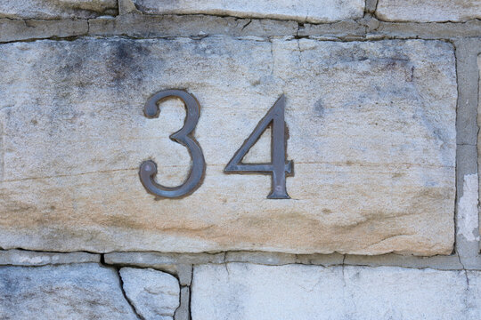 Number thityfour made with brass characters for address label on house. Number on rough sandstone background