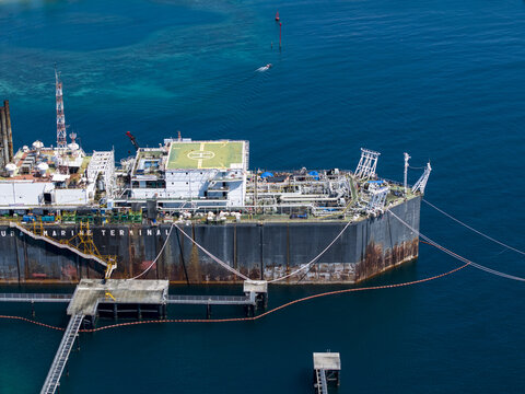 Aerial view of a Floating Storage and Offloading Ship moored at a marine terminal with industrial pipes, helipad, and steel structures in Buleleng Regency, Bali, Indonesia.