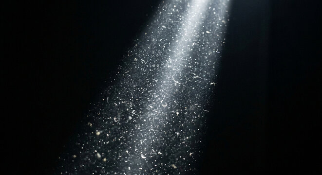 A bright beam of light shining through dark space with floating dust particles.