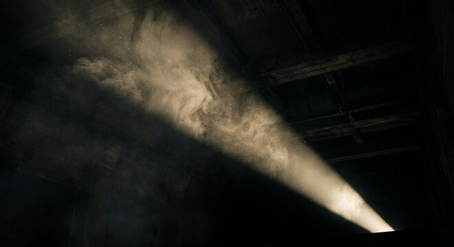 A dramatic beam of light cutting through dark dusty air in an old building.
