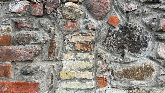 Close‑up of historic masonry built from irregular fieldstones and red brick fragments set in gray mortar, creating a richly textured architectural background with traditional craftsmanship.