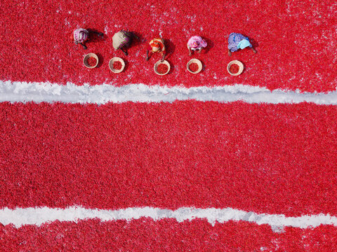 Aerial view of workers in colorful clothing sorting and drying vibrant red chilies in baskets on the ground in Bogura, Rajshahi Division, Bangladesh.