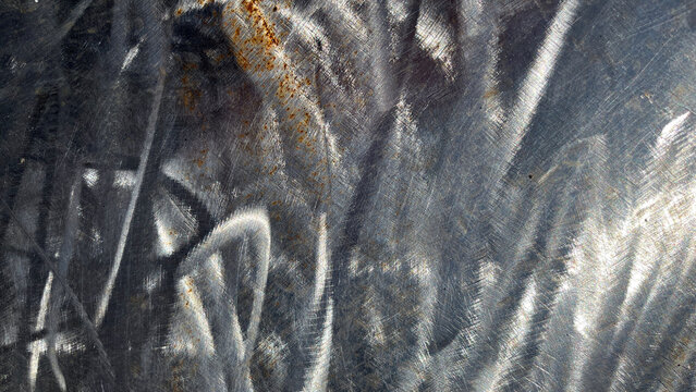 Close‑up of weathered galvanized metal sheet with scratches, reflective highlights, rust spots, and wavy distortions, creating an abstract industrial texture with metallic character.