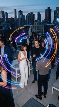 Rooftop party with vibrant neon light trails.