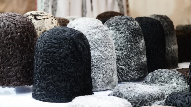Assortment of traditional astrakhan fur hats on display for sale at street market.