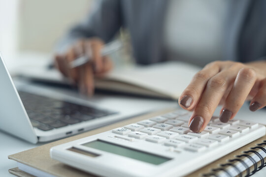 Close up business woman using calculator to calculate financial report and writing note, accounting on table at office, budget management, budgeting and tax calculation