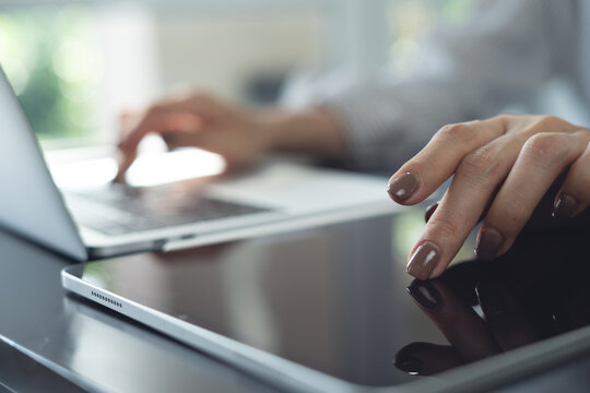 Close up, woman hand using digital tablet and working on laptop at office, surfing the net at modern workspace