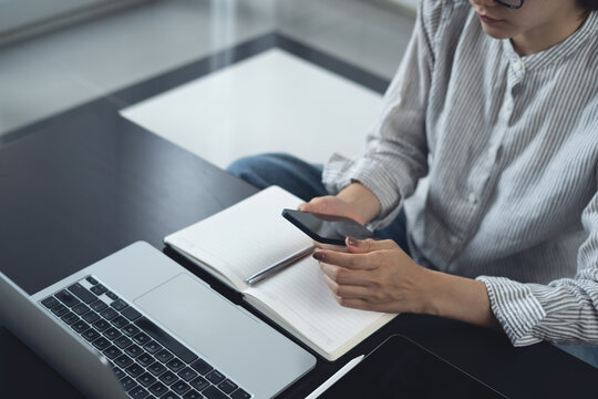 Woman sitting on the floor, remote working at home, using smartphone with digital tablet and laptop on table, online job, e-business concept