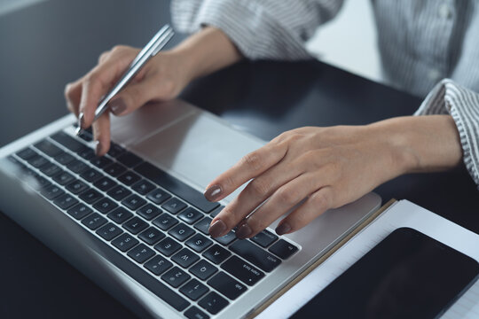 Close up of business woman working on laptop, surfing the net, searching the information and doing online research at office.