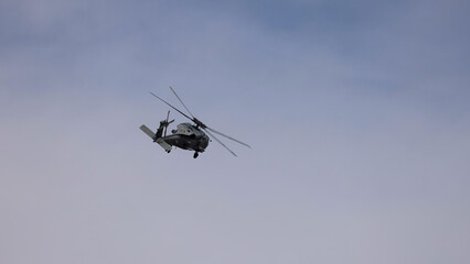 Fototapeta premium Military Helicopter Performing Aerial Maneuvers Against a Cloudy Sky