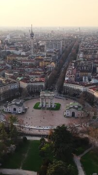 Aerial view of Arco della Pace in Milan with distant city skyline during golden hour.