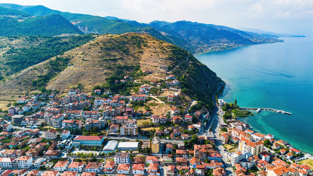 Aerial drone view of the historic Pogradec Castle hill, residential neighborhoods, and the shores of Lake Ohrid, Albania