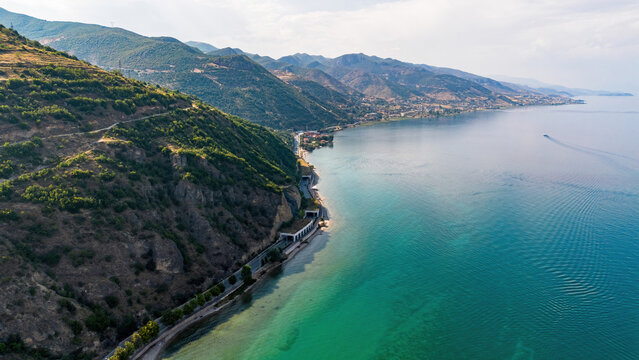 Aerial drone view of the coastal road, tunnels, and dramatic mountain slopes along the shores of Lake Ohrid near Pogradec, Albania
