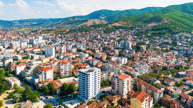 Aerial drone view of the dense urban neighborhoods, residential buildings, and green hills of Pogradec, Albania