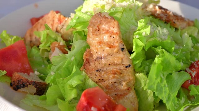 Fresh caesar salad with grilled chicken breast and crispy croutons served in ceramic bowl.