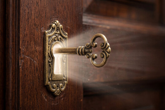 Antique brass skeleton key inserted into a decorative brass keyhole on a solid dark wooden door