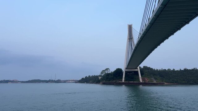 BATAM, INDONESIA - AUGUST 14 2026: Low angle view of the majestic Barelang Bridge (Tengku Fisabilillah) showing its cable-stayed architecture, concrete pylon, and the underside of the deck over the ca