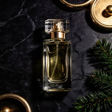 Sophisticated square glass perfume bottle with crystal stopper displayed on black marble with a fresh pine branch and antique gold ring accents.