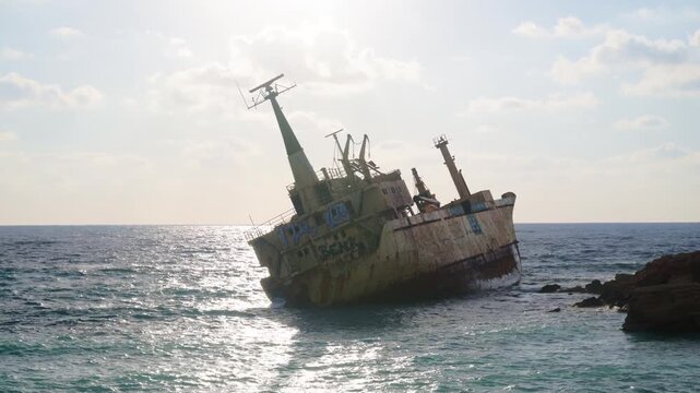 Abandoned shipwreck resting on rocky coast in Cyprus during sunny day.
