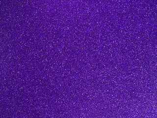Purple glitter texture. Shiny sparkling violet background. Bright grainy surface with light reflections. Festive abstract pattern for creative design.