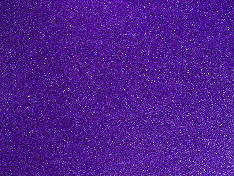Purple glitter texture. Shiny sparkling violet background. Bright grainy surface with light reflections. Festive abstract pattern for creative design.