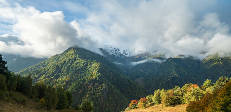 Landscape photograph of dramatic clouds and fog rolling over autumn mountain range in Svaneti Georgia.