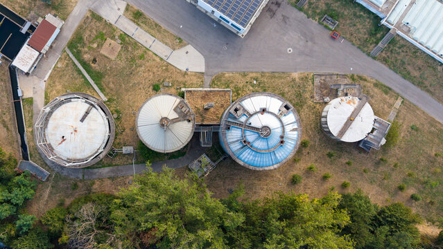 Aerial view of the wastewater treatment facility featuring circular anaerobic digesters for sludge treatment and biogas production in Assago, Lombardy, Italy.