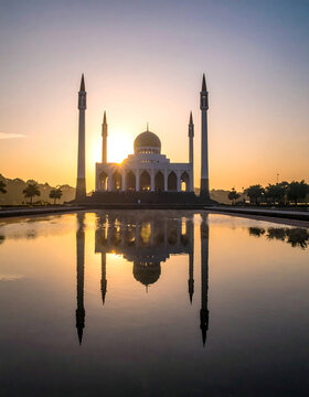 Majestic white mosque at sunset with stunning reflection in the water pool