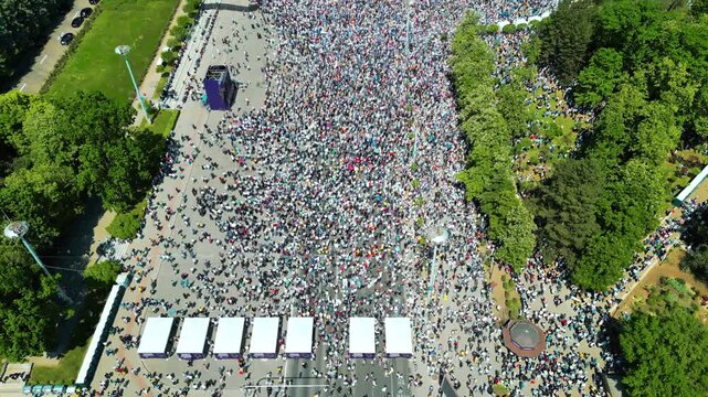 Aerial view of a massive crowd gathering in a public city square during a peaceful protest or political rally event.
