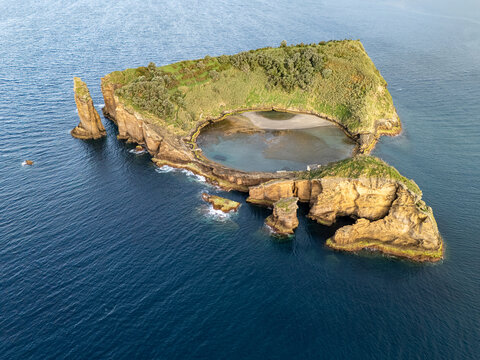 Aerial view of Ilheu de Vila Franca do Campo, a volcanic islet with a circular crater lagoon, surrounded by the Atlantic Ocean, featuring rugged cliffs in Sao Pedro, Acores, Portugal.