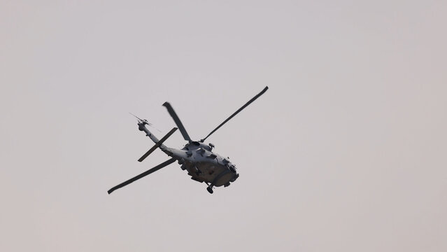 Military Helicopter Performing Dynamic Aerial Maneuvers Against a Cloudy Sky