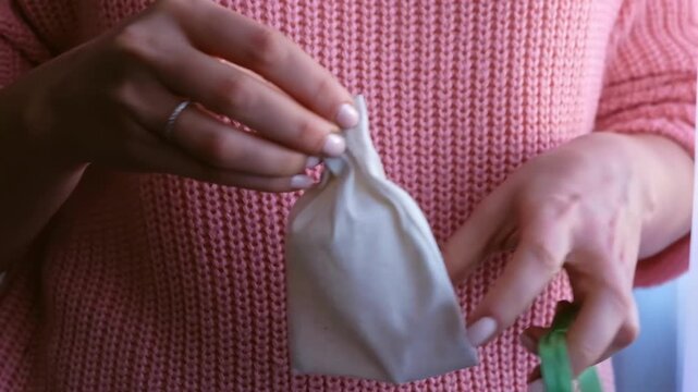 Woman removing white menstrual cup from small decorative fabric pouch.