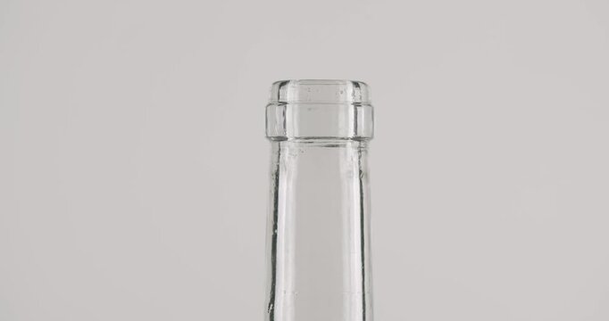 Slow motion close-up of a sommelier using a corkscrew to pull a natural cork stopper from a clear glass bottle, isolated on a clean white background, representing celebration and service