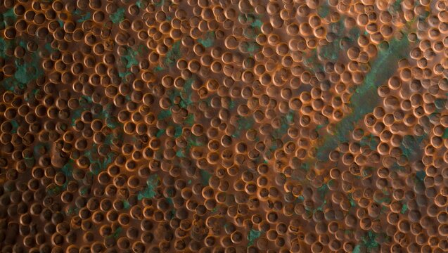 Closeup of hammered copper metal texture with green patina oxidation, rustic metallic surface background with circular indentations and weathered vintage finish