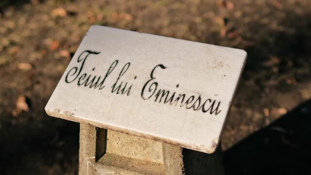 Stone plaque memorial plate featuring handwritten text dedicated to poet Mihai Eminescu in natural park setting.