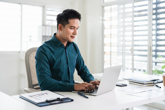 Happy professional business man company employee, young busy smiling male businessman entrepreneur or worker using laptop computer technology working at corporate office desk.