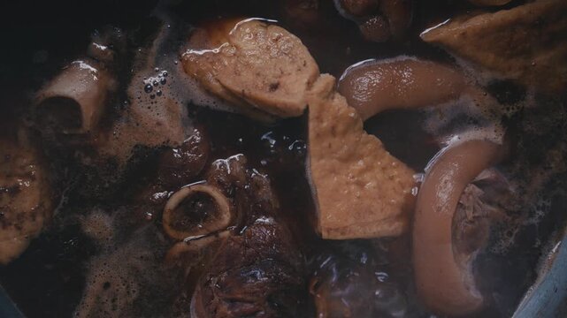 Slow motion of braised pork leg stew bubbling in cooking pot.