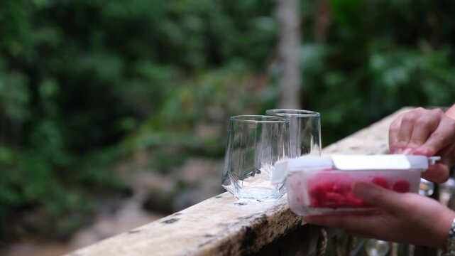 A woman putting raspberry in glasses to make a drinks