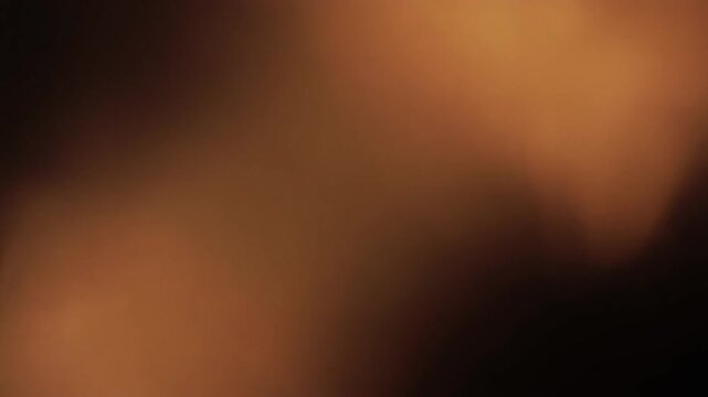 Warm amber light leak bleeds and spreads diagonally across a dark frame with soft organic edges, self-illuminated against total black &mdash; loop ideal for cinematic, retro, and film overlays.