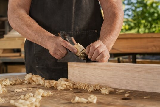 Skilled craftsman using vintage hand plane to shape light wood plank in well-lit workshop, traditional woodworking craftsmanship with fine shavings on rustic workbench