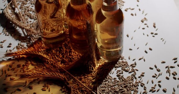Several swing top glass bottles of fresh light craft beer standing on a surface with malted barley grains, illustrating the brewing process and natural ingredients on a clean white background.